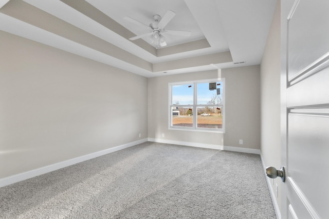 carpeted spare room featuring ceiling fan and a tray ceiling