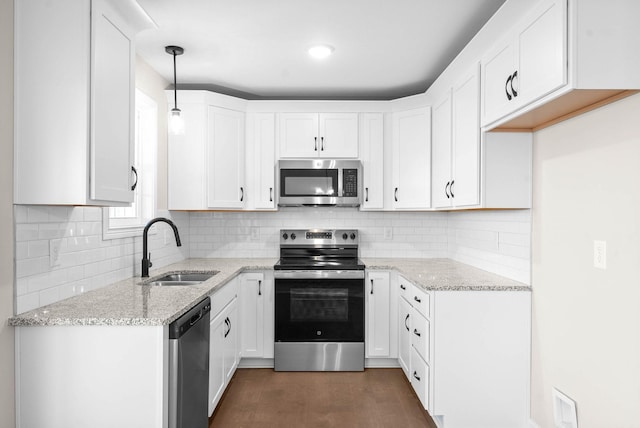 kitchen featuring decorative light fixtures, sink, white cabinetry, light stone countertops, and appliances with stainless steel finishes