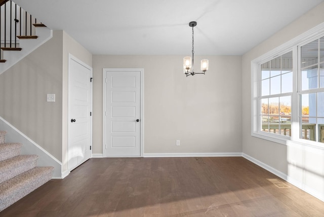 unfurnished dining area featuring dark hardwood / wood-style flooring and an inviting chandelier