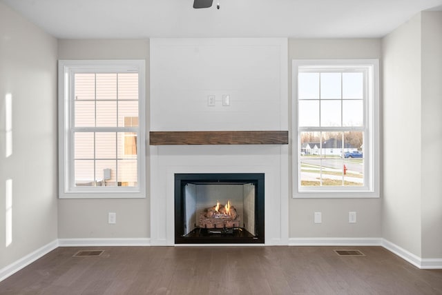 unfurnished living room featuring hardwood / wood-style flooring, a large fireplace, and ceiling fan