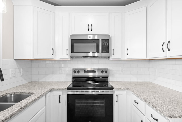 kitchen with decorative backsplash, white cabinets, and appliances with stainless steel finishes