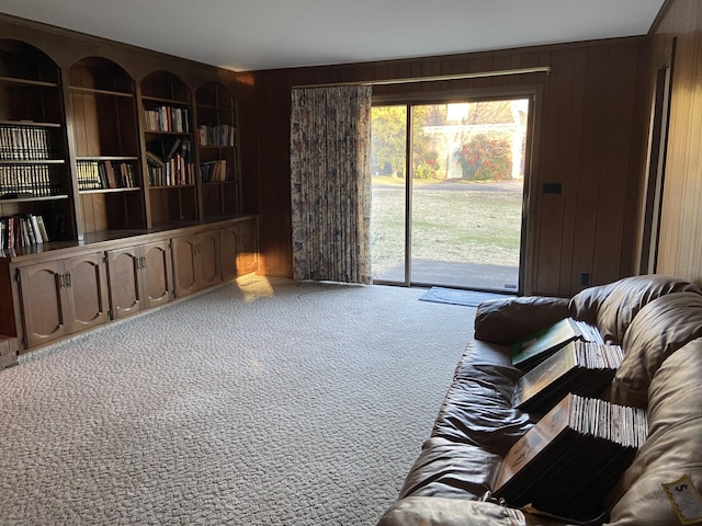 carpeted living room with built in shelves and wood walls