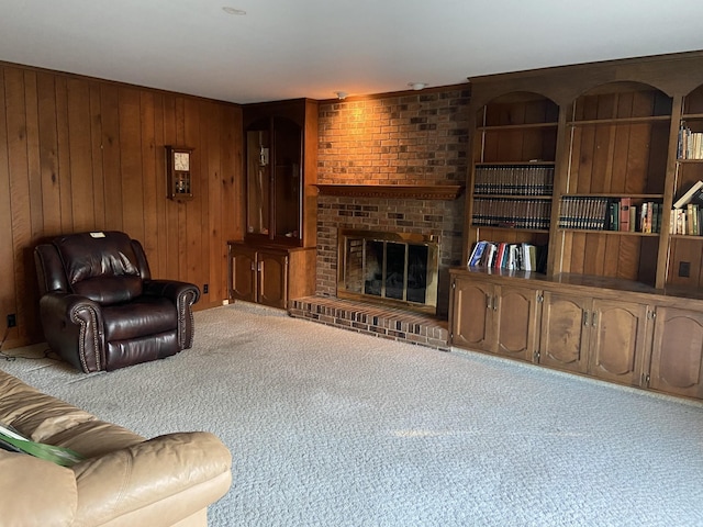 carpeted living room with wooden walls and a brick fireplace