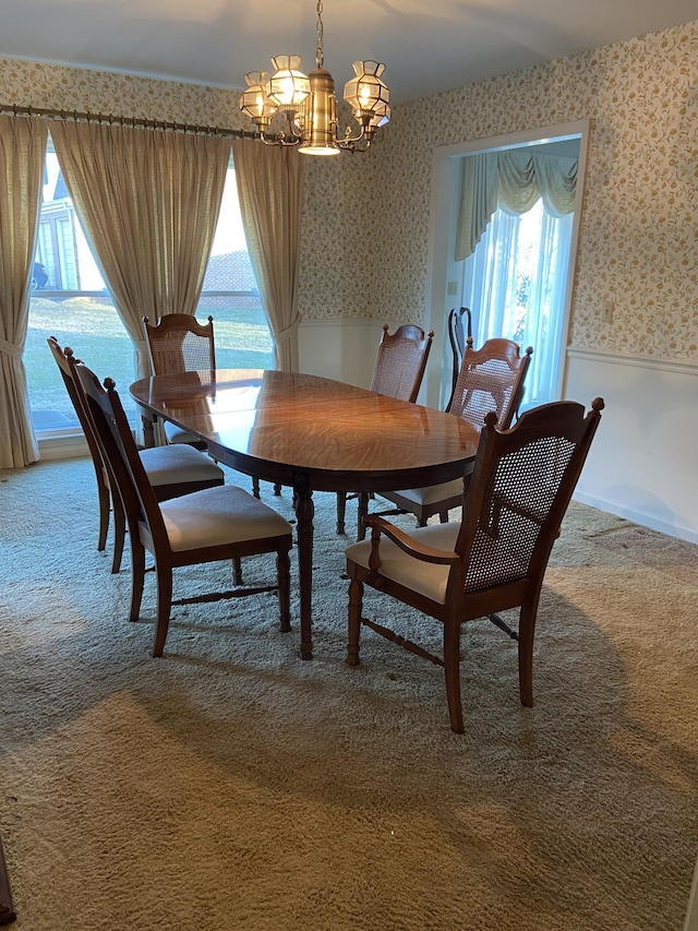 carpeted dining area with plenty of natural light, a notable chandelier, and a water view