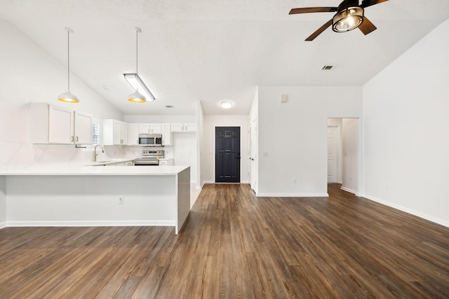 kitchen with kitchen peninsula, stainless steel appliances, lofted ceiling, white cabinets, and sink