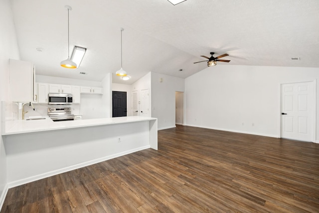 kitchen with decorative light fixtures, white cabinets, vaulted ceiling, kitchen peninsula, and appliances with stainless steel finishes