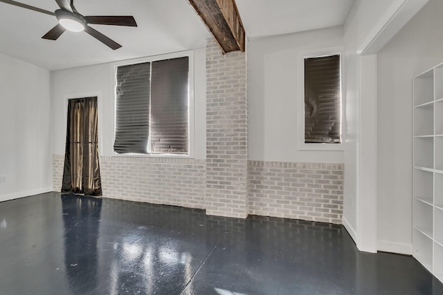 unfurnished room featuring beam ceiling, ceiling fan, and brick wall