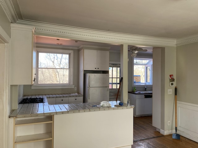 kitchen featuring white refrigerator, tile countertops, stainless steel gas stovetop, crown molding, and dark wood-type flooring