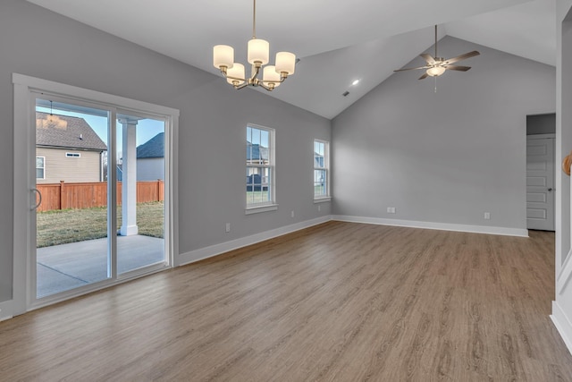 interior space with ceiling fan with notable chandelier, a wealth of natural light, lofted ceiling, and light hardwood / wood-style floors