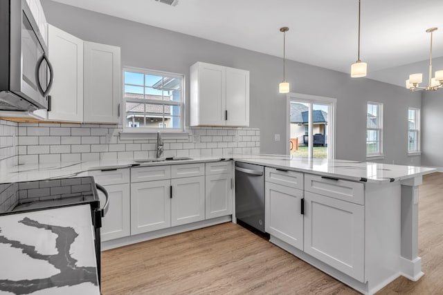 kitchen featuring kitchen peninsula, pendant lighting, white cabinets, and stainless steel appliances