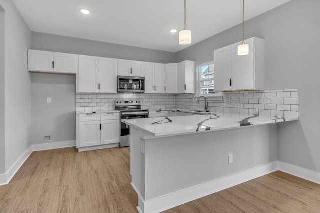 kitchen featuring decorative light fixtures, white cabinetry, stainless steel appliances, sink, and kitchen peninsula