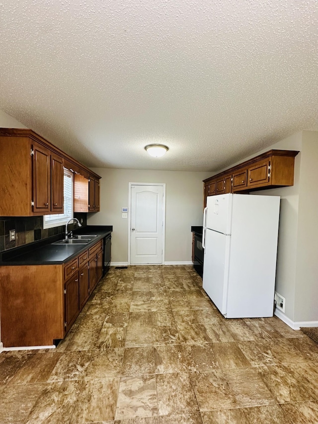 kitchen featuring white fridge, a textured ceiling, black dishwasher, and sink