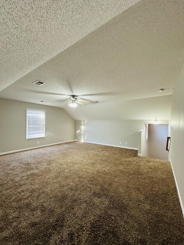 additional living space featuring a textured ceiling, vaulted ceiling, and carpet floors