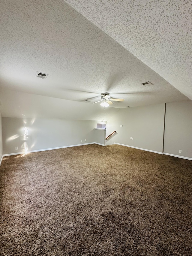 interior space with a textured ceiling, ceiling fan, and carpet