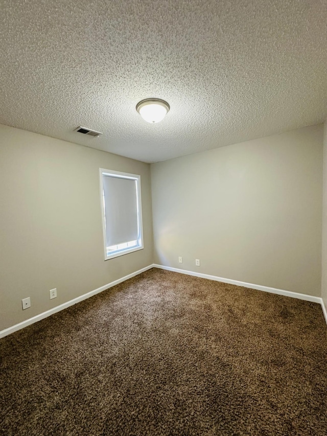 carpeted empty room featuring a textured ceiling