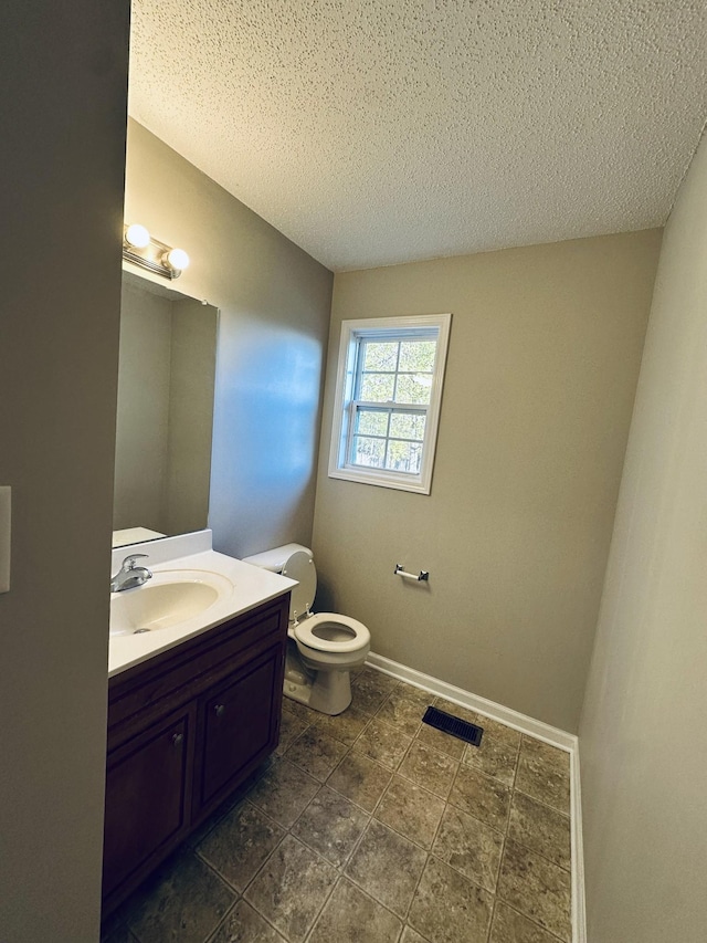 bathroom with toilet, a textured ceiling, and vanity