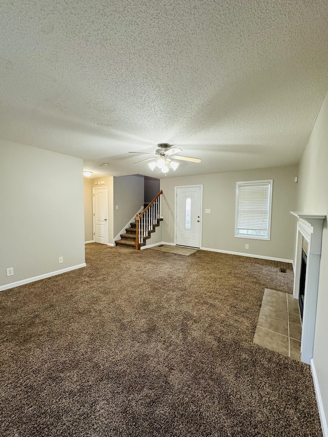 unfurnished living room featuring a textured ceiling, ceiling fan, and carpet