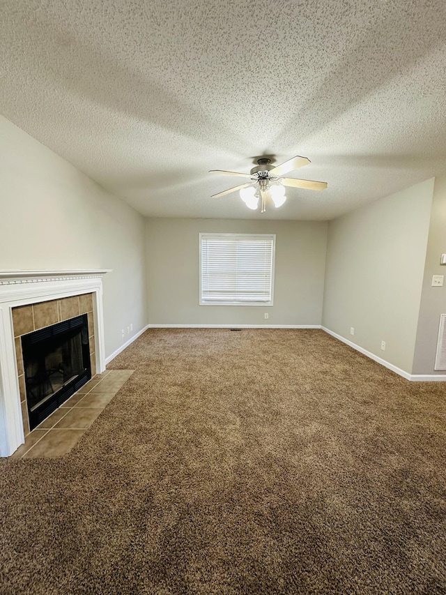 unfurnished living room featuring ceiling fan, light colored carpet, a tile fireplace, and a textured ceiling