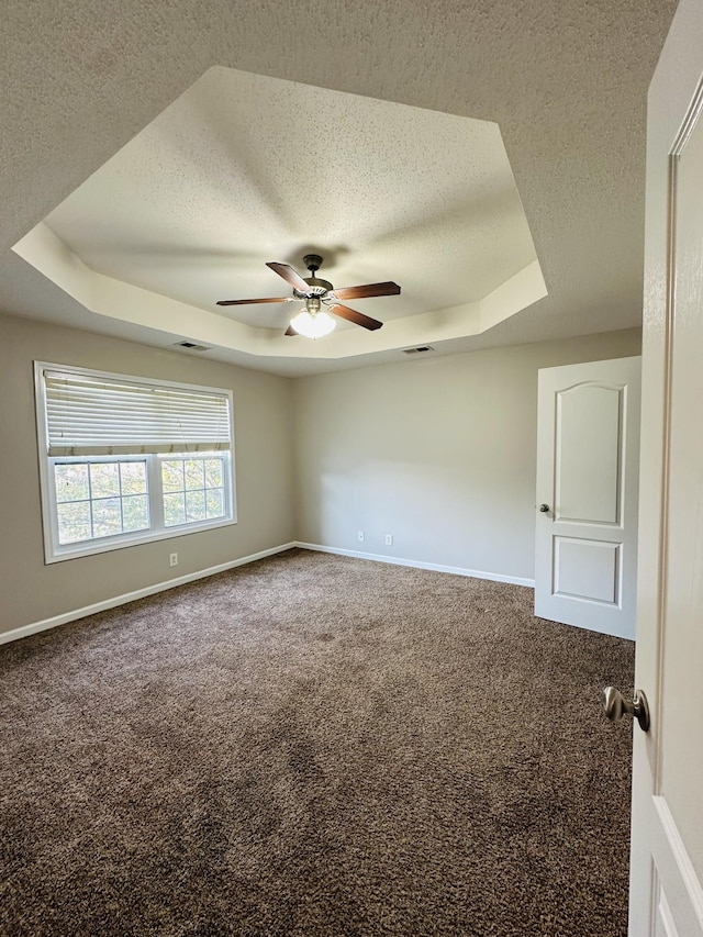 spare room featuring a textured ceiling, ceiling fan, a tray ceiling, and carpet floors