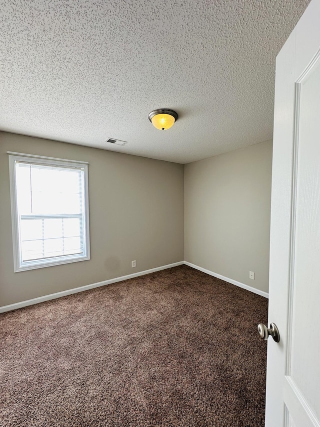 unfurnished room featuring a textured ceiling and carpet flooring