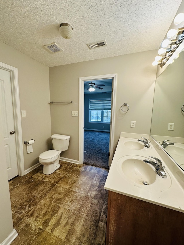 bathroom with a textured ceiling, ceiling fan, vanity, and toilet