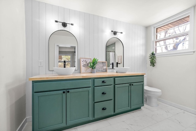 bathroom featuring toilet, vanity, and wood walls