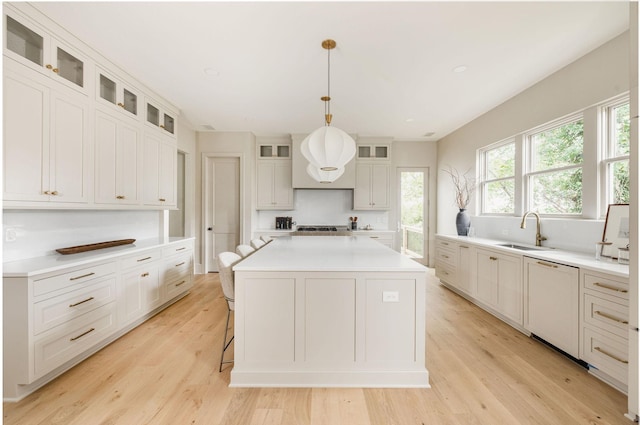 kitchen featuring a center island, hanging light fixtures, paneled dishwasher, light wood-type flooring, and sink