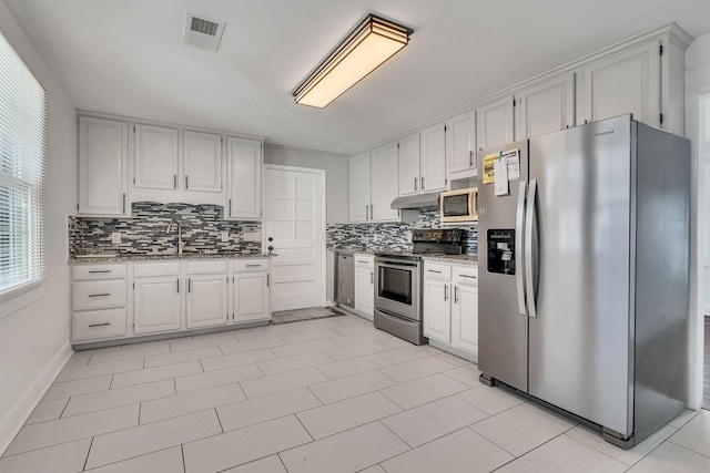 kitchen with white cabinets, appliances with stainless steel finishes, sink, and dark stone countertops