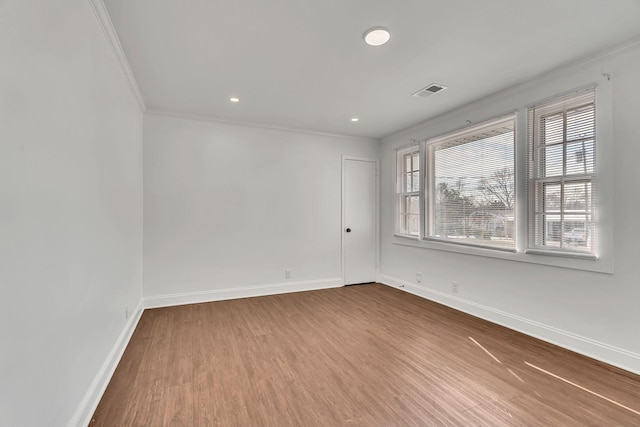 spare room featuring hardwood / wood-style flooring, plenty of natural light, and crown molding