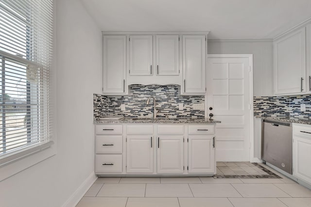 kitchen with light tile patterned floors, dishwasher, white cabinets, and sink