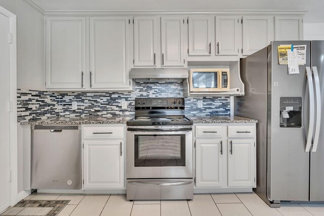 kitchen featuring light stone countertops, light tile patterned floors, appliances with stainless steel finishes, and white cabinetry