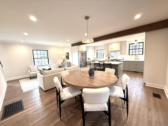 dining room with beam ceiling, crown molding, sink, and dark hardwood / wood-style flooring