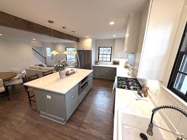 kitchen featuring gray cabinets, dark wood-type flooring, high end fridge, a kitchen island, and decorative light fixtures