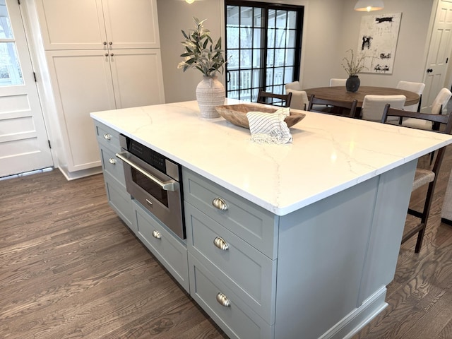 kitchen featuring dark wood-type flooring, a kitchen island, oven, and a breakfast bar area