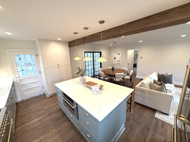 kitchen with pendant lighting, beam ceiling, a center island, and dark wood-type flooring