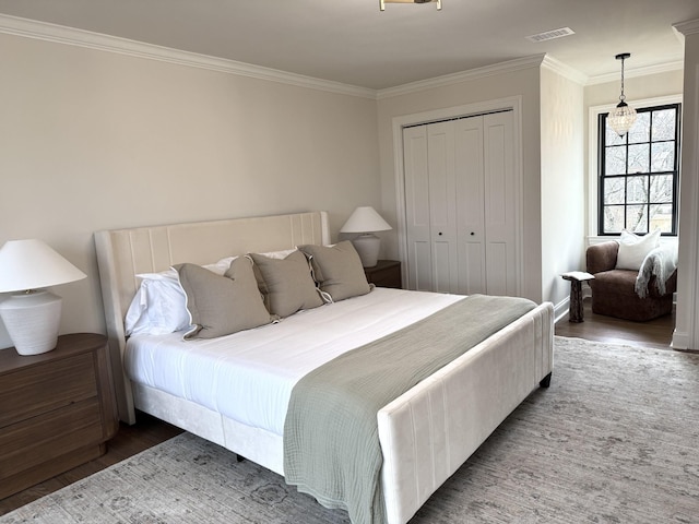 bedroom featuring crown molding, a notable chandelier, dark hardwood / wood-style flooring, and a closet