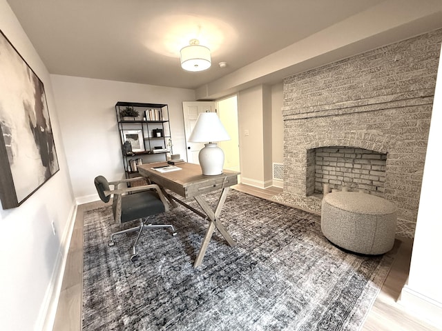 office space with wood-type flooring and a fireplace