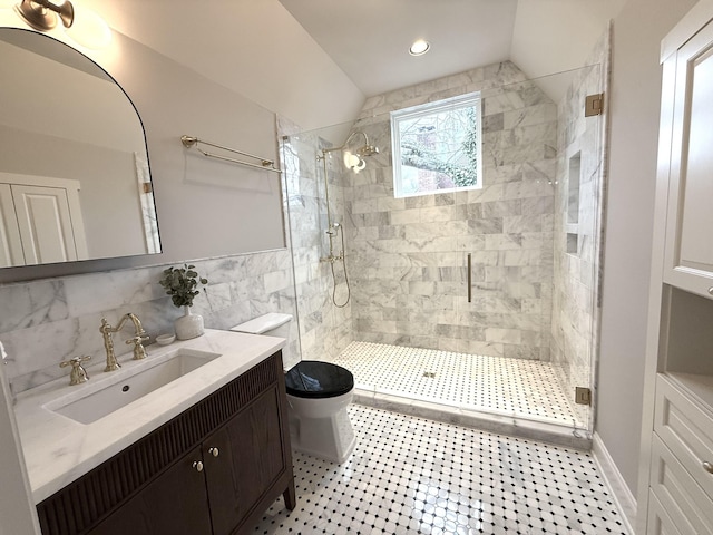 bathroom featuring vaulted ceiling, a shower with shower door, tile walls, vanity, and toilet