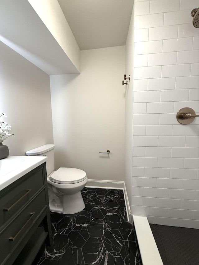 bathroom featuring vanity, toilet, and a tile shower