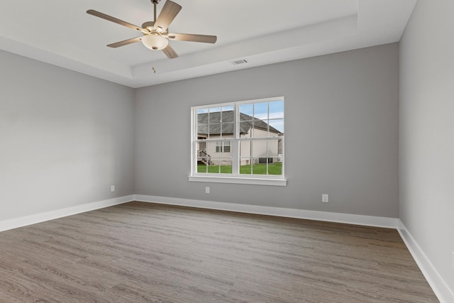 spare room featuring ceiling fan, hardwood / wood-style floors, and a raised ceiling