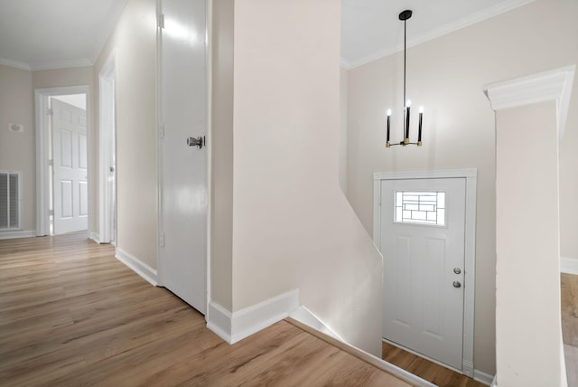 foyer with hardwood / wood-style floors, crown molding, and a chandelier