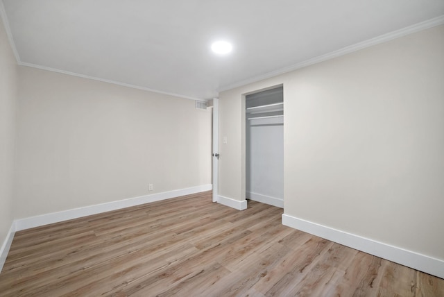 unfurnished bedroom featuring light hardwood / wood-style floors, crown molding, and a closet