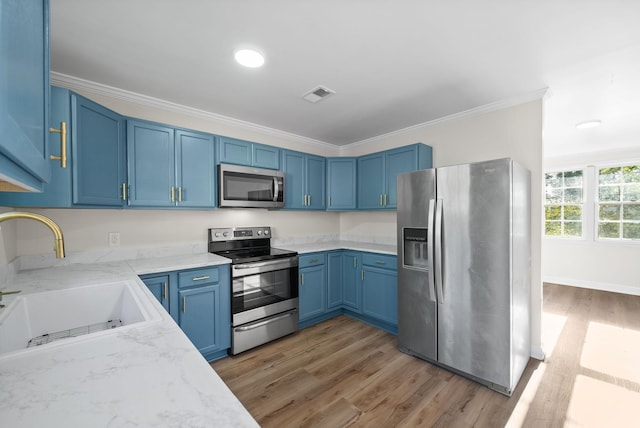 kitchen with light stone counters, stainless steel appliances, crown molding, blue cabinetry, and sink