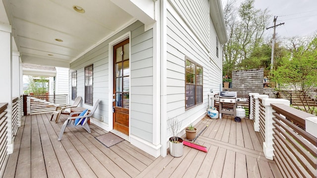 wooden terrace featuring covered porch and a grill