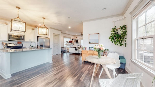 kitchen featuring light stone counters, decorative light fixtures, backsplash, white cabinets, and appliances with stainless steel finishes