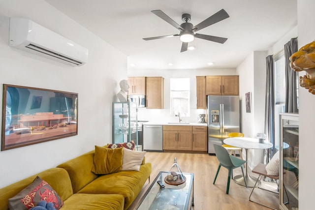 living room with sink, a healthy amount of sunlight, light hardwood / wood-style flooring, and a wall mounted air conditioner