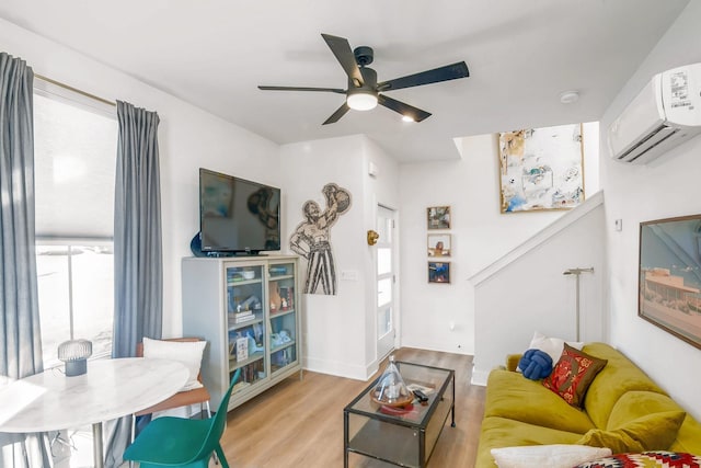 living room with an AC wall unit, ceiling fan, and light hardwood / wood-style floors