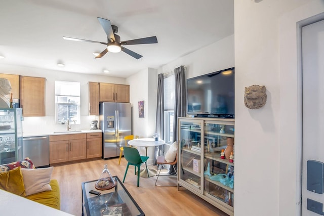 kitchen featuring sink, ceiling fan, light hardwood / wood-style flooring, decorative backsplash, and appliances with stainless steel finishes