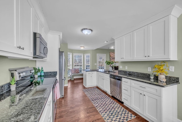 kitchen with appliances with stainless steel finishes, white cabinetry, sink, and kitchen peninsula