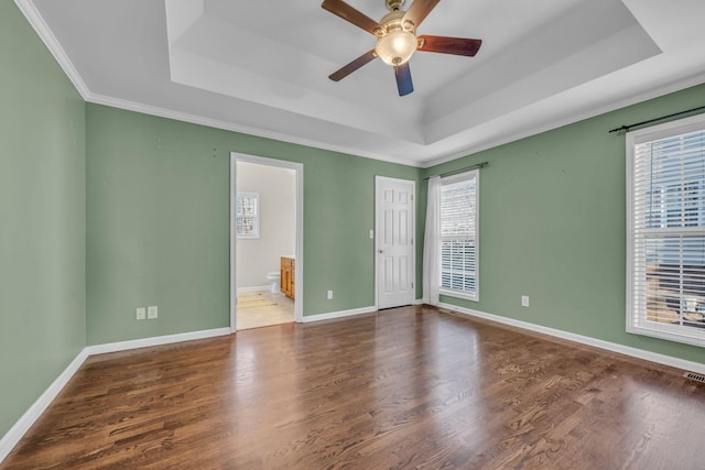 spare room with wood-type flooring, ceiling fan, a tray ceiling, and ornamental molding